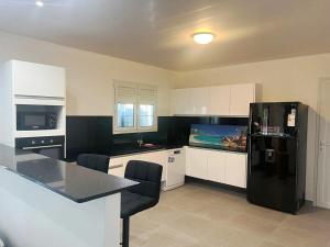 una cucina con frigorifero nero e armadietti bianchi di Belle petite maison Les Trois-Îlets a Les Trois-Îlets
