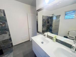 un bagno bianco con lavandino e specchio di Belle petite maison Les Trois-Îlets a Les Trois-Îlets