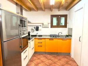 een keuken met oranje kasten en een roestvrijstalen koelkast bij A Casa de Feli in Muros