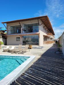a villa with a swimming pool and a house at Pontal Flat 103 in Coruripe