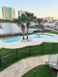 a swimming pool with palm trees and a fence at Bayou Breeze Retreat in Orange Beach