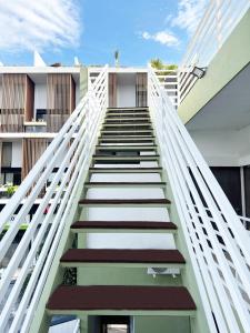 eine Treppe, die zu einem Gebäude mit weißem Geländer hinaufführt in der Unterkunft SILVERSANDS Hotel Boutique - 5Th Ave in Playa del Carmen