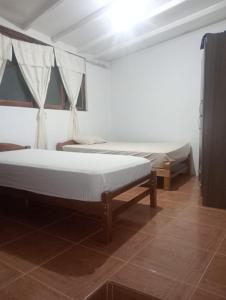 een kamer met 2 bedden in een kamer met houten vloeren bij Casa Zorritos in Zorritos