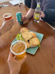 Twee mensen zitten aan een tafel met een sandwich en drankjes. bij Aldea del Sur Hostel by Indomito Sur in Punta Arenas +24 foto's