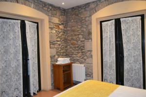 a bedroom with two windows and a stone wall at Apartments Historic in Girona