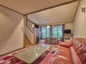 een woonkamer met een leren bank en een tafel bij Runesu Karuizawa - Vacation STAY 78421v in Tsumagoi