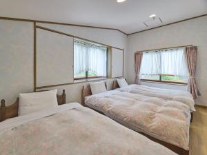 twee bedden in een kamer met twee ramen bij Runesu Karuizawa - Vacation STAY 78421v in Tsumagoi