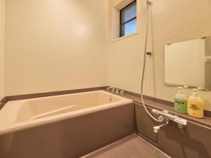 een badkamer met een bad en een spiegel bij Runesu Karuizawa - Vacation STAY 78421v in Tsumagoi +43 foto's