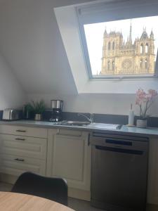 a kitchen with a sink and a window with a building at Vue Cathedrale, Elegance & Lumière à Amiens in Amiens +5 photos