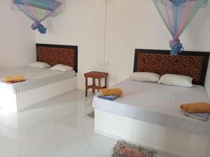 twee bedden in een kamer met witte muren bij The Banana Cottage in Udawalawe +24 foto's