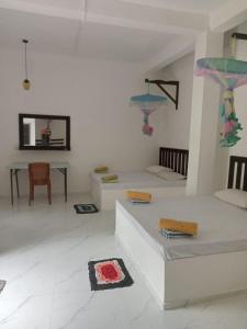 een witte woonkamer met 2 bedden en een tafel bij The Banana Cottage in Udawalawe