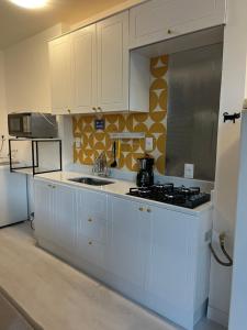 a kitchen with white cabinets and a stove top oven at Apartamento Charme da Glória in Rio de Janeiro
