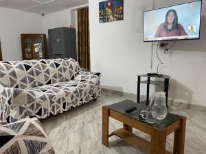 een woonkamer met een bank en een flatscreen-tv bij Lege Bonoua in Bonoua