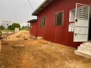 een rood huis met een onverharde tuin naast een gebouw bij Lege Bonoua in Bonoua
