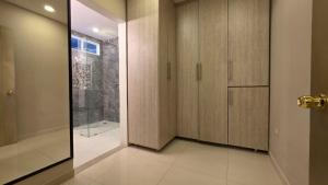 ein Badezimmer mit Holzschränken und einer Glastür in der Unterkunft Hotel Casa La Tablada Aeropuerto in Cartagena de Indias