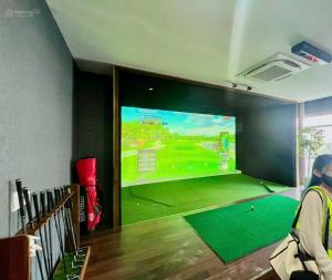 a room with a large screen showing a golf game at Happy One Central in Trạm Chánh An