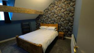 een slaapkamer met een bed met een stenen muur bij The Maisonette central Buxton in Buxton