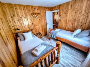 twee bedden in een kamer met houten wanden bij Complejo "Nahuel Pan " in El Chalten