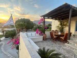 a patio with a white couch and a table with pink flowers at Villa Loretta with pool, jacuzzi and garden in Posidhonía