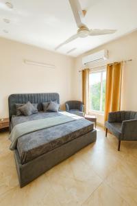 ein Schlafzimmer mit einem großen Bett und zwei Stühlen in der Unterkunft The Atelier G-13 in Islamabad