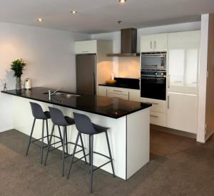 a kitchen with white cabinets and a black island with bar stools at Apartment 303 Tauranga in Tauranga