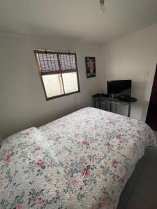 a bedroom with a bed with a floral bedspread and a window at Gadir hostel in Coquimbo