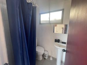 a bathroom with a toilet and a blue shower curtain at Gadir hostel in Coquimbo