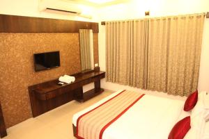 a hotel room with a bed and a television at Hotel Sai Ramanand in Shirdi