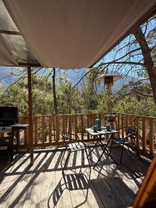een veranda met een tafel en stoelen op een terras bij Glamping MORET Tiny House M1 in Los Lirios