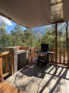 a patio with a table and a grill on a deck at Glamping MORET Tiny House M1 in Los Lirios