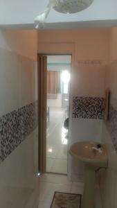 een badkamer met een wastafel en een deur naar een gang bij Pousada Enseada do Coqueiro in Guarapari