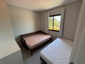 une petite chambre avec deux lits et une fenêtre dans l'établissement Apartamento Ju & Mar, à Itapoá