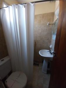 een badkamer met een wit douchegordijn en een wastafel bij Florencia Apartamentos y habitaciones in Necochea +14 foto's