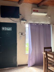 une pièce avec une porte, une télévision et une fenêtre dans l'établissement Cab19,Anisacate, à Alta Gracia