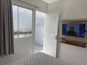 een slaapkamer met een tv aan een witte muur bij Loft novo e bem localizado in Biguaçu