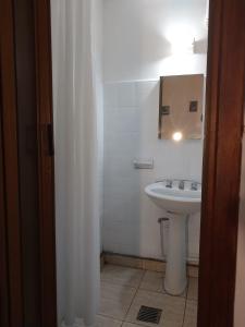 een witte badkamer met een wastafel en een spiegel bij Florencia Apartamentos y habitaciones in Necochea