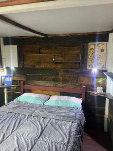- une chambre avec un lit et un mur en bois dans l'établissement El Antiguo, à Cabo Polonio