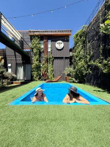 two women laying in a swimming pool in the grass at Casa Panal , Jacuzzi opcional Villa Alemana in Villa Alemana