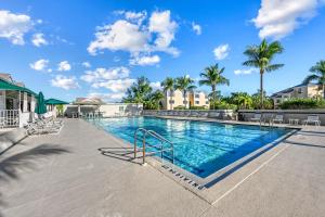 a swimming pool at a resort with chairs and palm trees at Starfish Sands - 580 in Longboat Key