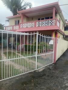 een roze huis met een wit hek bij Shantee Residence in Trou dʼ Eau Douce