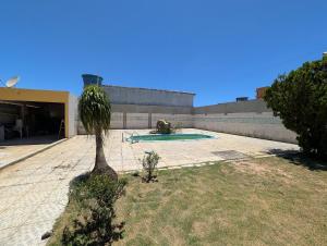palma di fronte a un edificio con piscina di Casa Temporada Refúgio das Ondas a Guriri