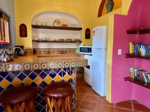 a kitchen with a bar with a white refrigerator at Luna - Casa MoJo's delightful 1BR, kitchen, pool in Sayulita