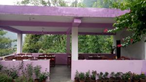 een paars paviljoen met tafels, stoelen en planten bij Hotel evergreen lodge in Kāskī +8 foto's