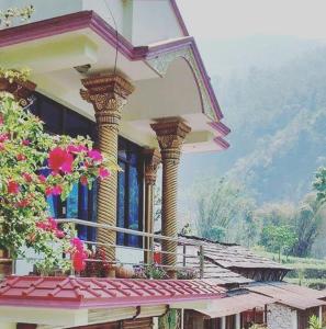 een gebouw met zuilen en bloemen op een balkon bij Hotel evergreen lodge in Kāskī