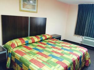 a hotel room with a bed with a colorful quilt at Scottish Inn & Suites Hobby Airport in Houston