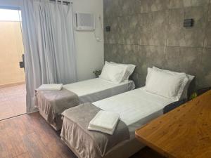 two beds in a room with white sheets and pillows at Pousada Verde Serrath - Muriqui in Vila Muriqui