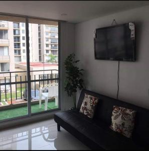 een woonkamer met een zwarte bank en een flatscreen-tv bij Caranday, Las Palmas in Ricaurte