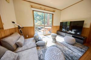 een woonkamer met een bank en een flatscreen-tv bij BLUEBAY TERRACE okutama in Okutama