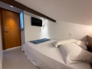 a bedroom with a bed with a television on the wall at Triplex Luxo 2 Qtos c Churrasqueira na Rua das Pedras in Búzios