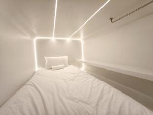 een witte kamer met een bed met lichten erop bij The Rich Cafe & Hostel in Pattaya South +2 foto's